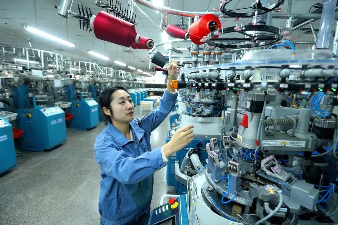 Operator running a knitting machine in a Chinese textile factory
